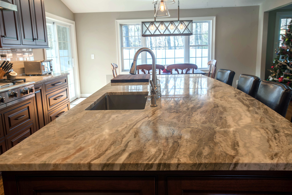 Example of a mid-sized galley medium tone wood floor eat-in kitchen design in New York with an undermount sink, raised-panel cabinets, dark wood cabinets, quartzite countertops, white backsplash, ceramic backsplash, stainless steel appliances and an island