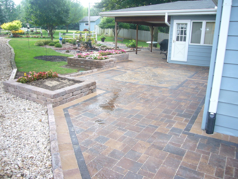 Photo of a large traditional backyard patio in Omaha with brick pavers and a roof extension.