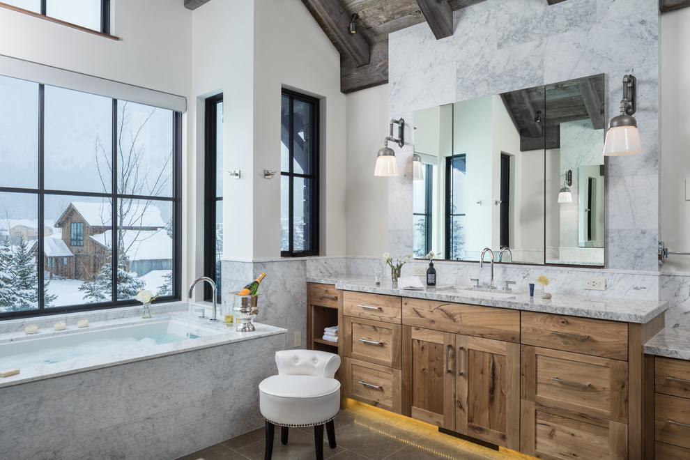 Inspiration for a country bathroom in Jackson with gray tile, marble benchtops, grey benchtops, shaker cabinets, medium wood cabinets, an undermount tub, marble, white walls, an undermount sink and grey floor.