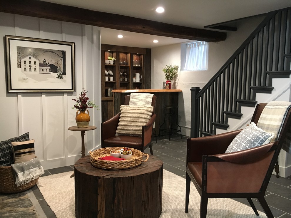 Photo of a mid-sized country walk-out basement in Philadelphia with white walls, a wood stove, a stone fireplace surround, grey floor and slate floors.