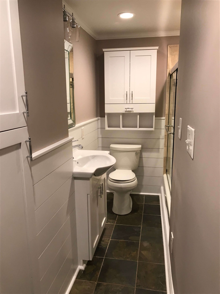 Photo of a small transitional 3/4 bathroom in DC Metro with recessed-panel cabinets, white cabinets, an undermount tub, a shower/bathtub combo, a one-piece toilet, beige tile, travertine, beige walls, slate floors, a console sink, glass benchtops, brown floor, a sliding shower screen, white benchtops, a niche, a single vanity, a built-in vanity and panelled walls.