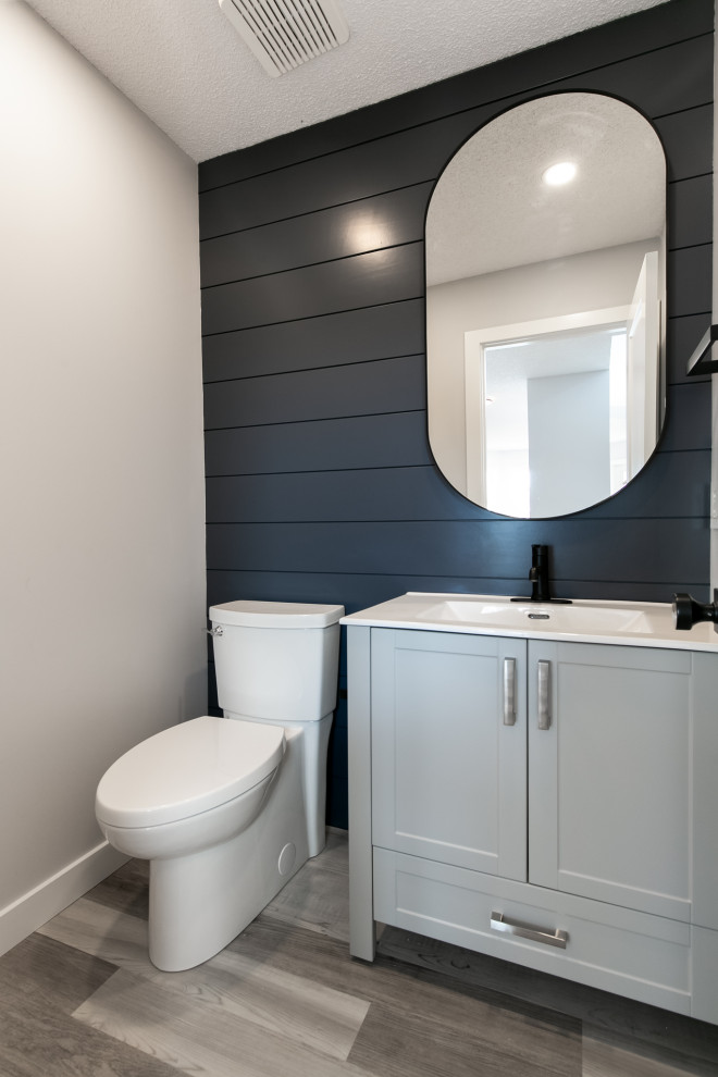 Example of a transitional blue tile gray floor and shiplap wall powder room design in Calgary with shaker cabinets, gray cabinets, a two-piece toilet, gray walls, an undermount sink, quartz countertops, white countertops and a freestanding vanity