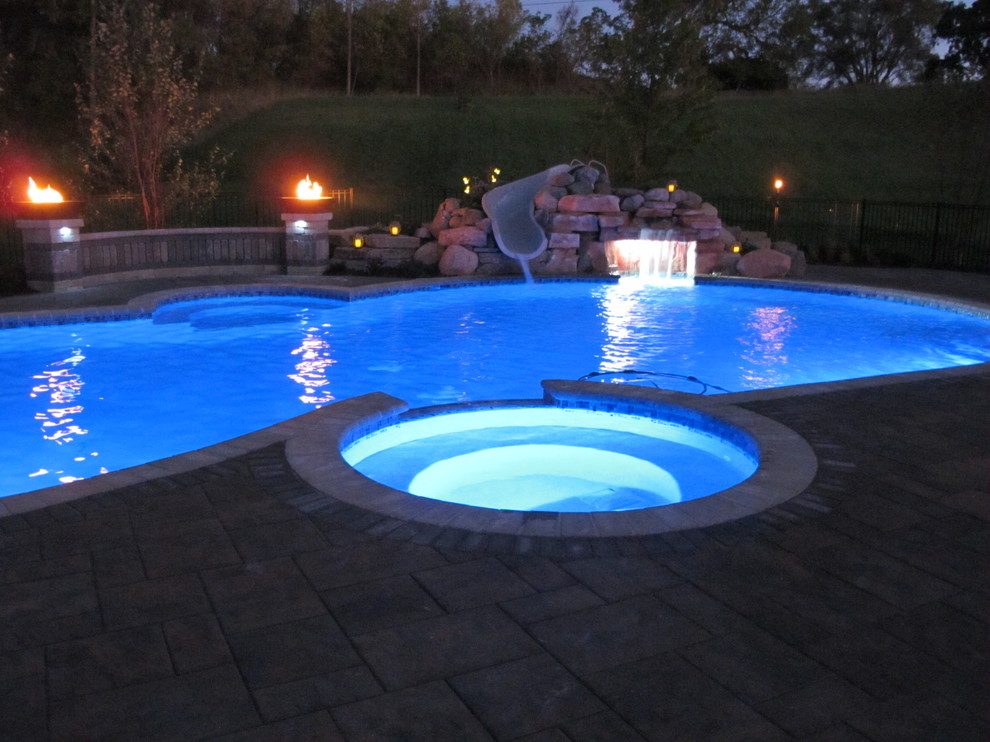 Inspiration for a transitional backyard custom-shaped pool in Detroit with a hot tub and brick pavers.