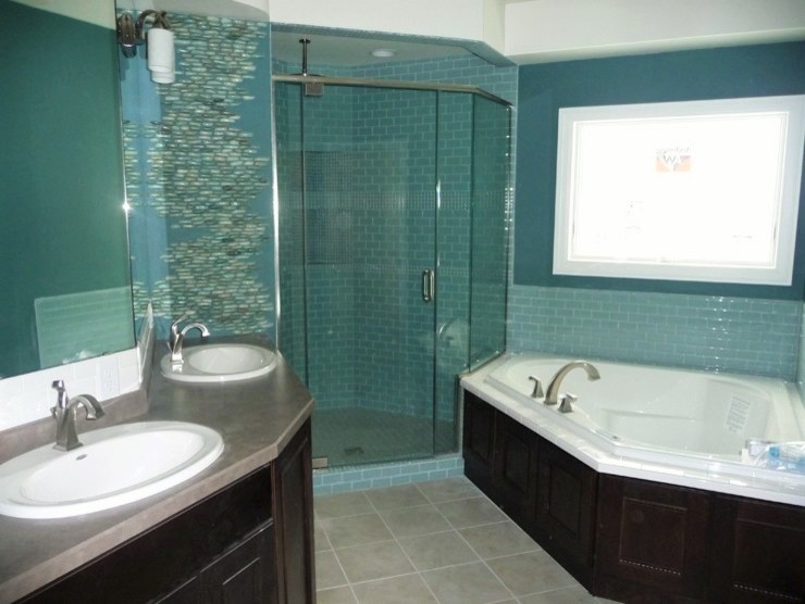 Photo of a mid-sized transitional master bathroom in Other with recessed-panel cabinets, dark wood cabinets, a corner tub, a corner shower, blue walls, a drop-in sink, laminate benchtops, ceramic floors, subway tile, blue tile, grey floor and a hinged shower door.