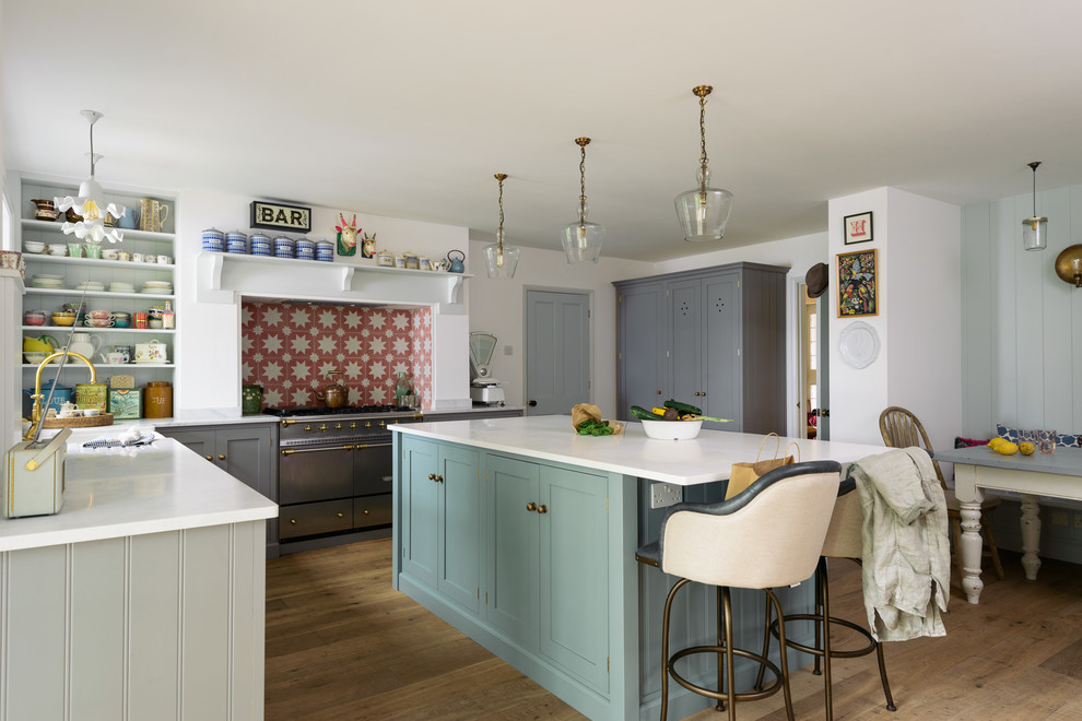 Design ideas for a mid-sized contemporary l-shaped eat-in kitchen in Other with a double-bowl sink, shaker cabinets, grey cabinets, orange splashback, ceramic splashback, stainless steel appliances, medium hardwood floors, with island and brown floor.