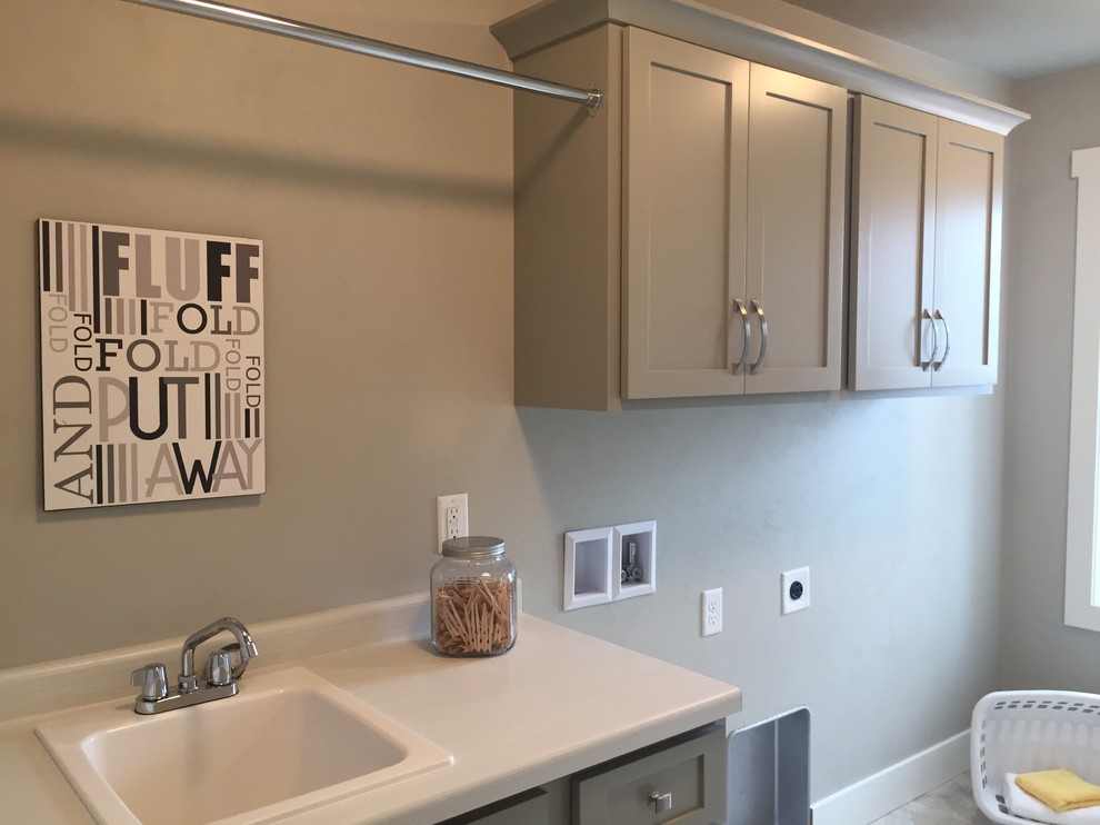 Design ideas for a mid-sized contemporary single-wall dedicated laundry room in Milwaukee with a drop-in sink, shaker cabinets, grey cabinets, laminate benchtops, grey walls, vinyl floors and a side-by-side washer and dryer.