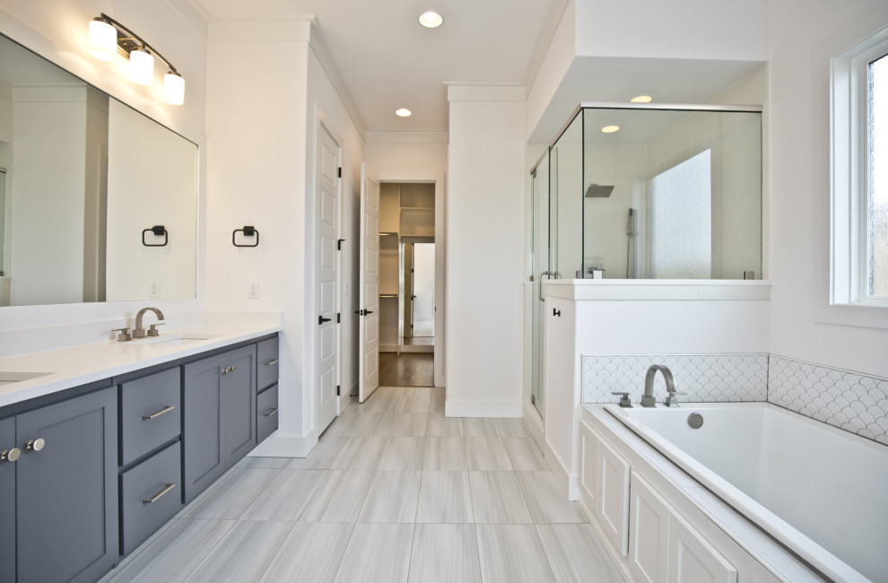 Photo of a mid-sized traditional master bathroom in Other with shaker cabinets, grey cabinets, a drop-in tub, a corner shower, white walls, porcelain floors, an undermount sink, engineered quartz benchtops, grey floor, a hinged shower door and white benchtops.