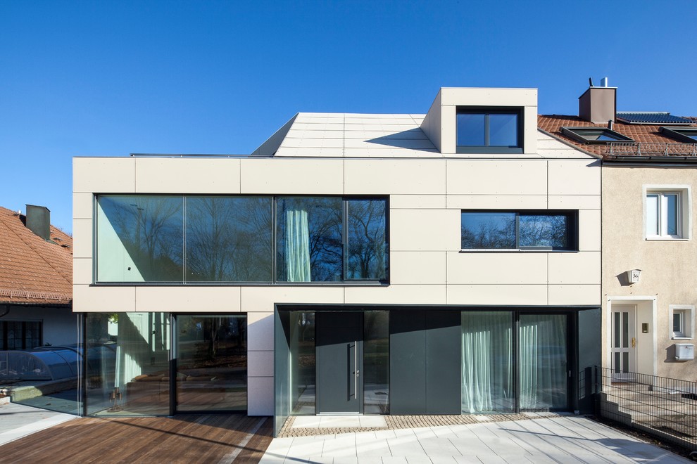 Mid-sized contemporary three-storey beige exterior in Munich with a gable roof and concrete fiberboard siding.