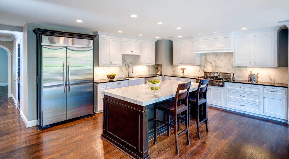 Design ideas for a large traditional l-shaped eat-in kitchen in DC Metro with a farmhouse sink, flat-panel cabinets, white cabinets, granite benchtops, white splashback, stone slab splashback, stainless steel appliances, medium hardwood floors and with island.