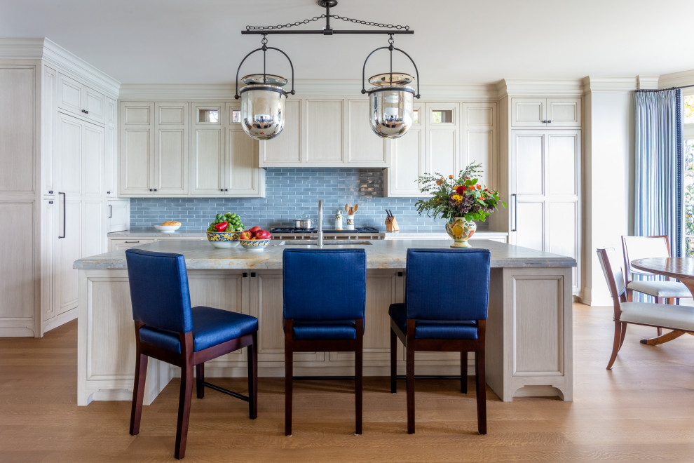 Example of a transitional medium tone wood floor and brown floor eat-in kitchen design in Chicago with an undermount sink, recessed-panel cabinets, light wood cabinets, blue backsplash, paneled appliances, an island and gray countertops