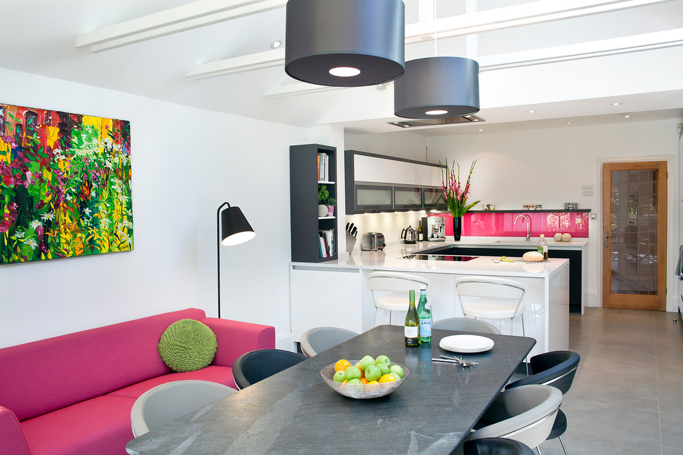 Photo of a large contemporary u-shaped eat-in kitchen in London with pink splashback, glass sheet splashback, a peninsula, flat-panel cabinets, black cabinets, solid surface benchtops, porcelain floors and grey floor.