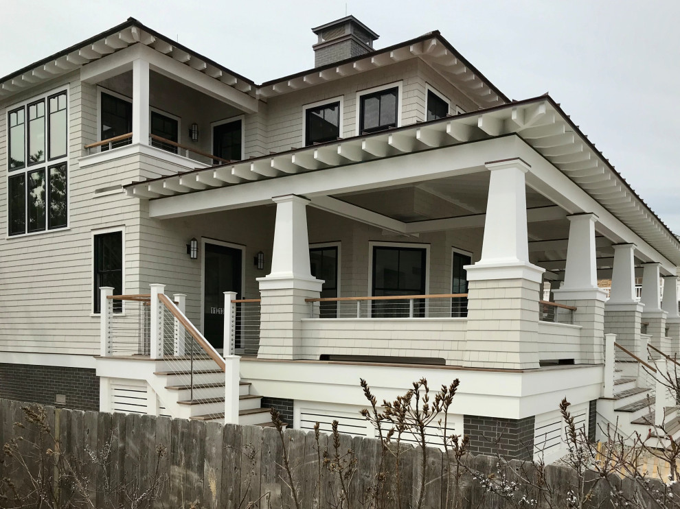 Inspiration for a mid-sized beach style two-storey beige house exterior in New York with wood siding, a hip roof, a shingle roof, a brown roof and shingle siding.