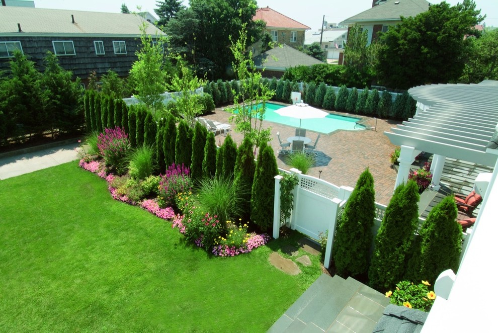 Large traditional backyard full sun formal garden in New York with a garden path and natural stone pavers for summer.