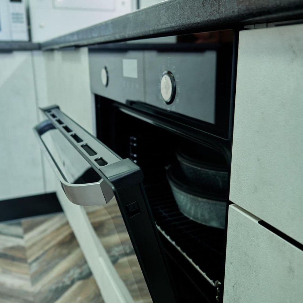 Белая угловая кухня с высокими шкафами и черной столешницей