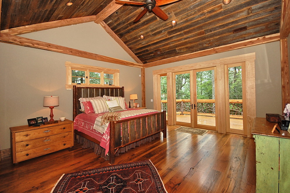 This is an example of a large country master bedroom in Other with beige walls, medium hardwood floors and brown floor.