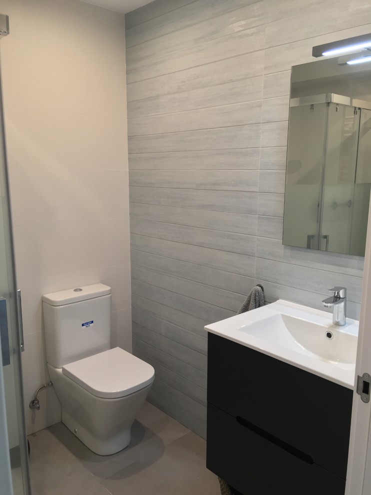 This is an example of a mid-sized scandinavian 3/4 bathroom in Other with flat-panel cabinets, white cabinets, a curbless shower, a one-piece toilet, white tile, ceramic tile, white walls, ceramic floors, a drop-in sink, grey floor and white benchtops.
