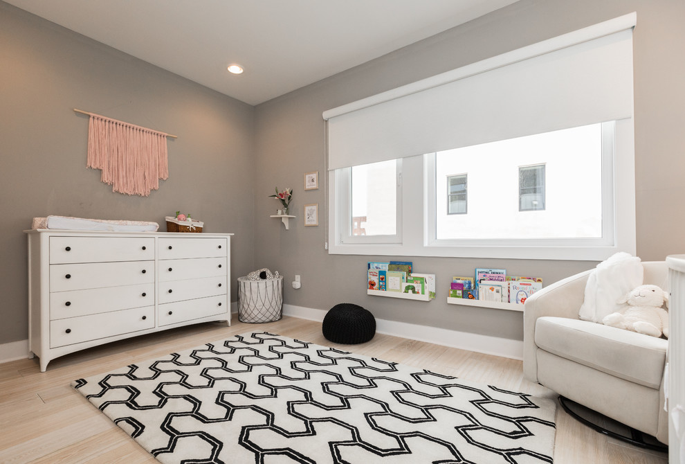 Mid-sized modern nursery in Philadelphia with grey walls, light hardwood floors and beige floor for girls.
