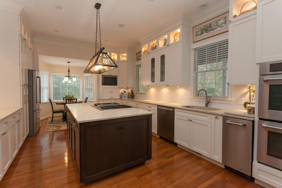 Design ideas for an expansive traditional u-shaped eat-in kitchen in Charleston with with island, recessed-panel cabinets, white cabinets, recycled glass benchtops, an undermount sink, white splashback, ceramic splashback, stainless steel appliances, medium hardwood floors and beige floor.