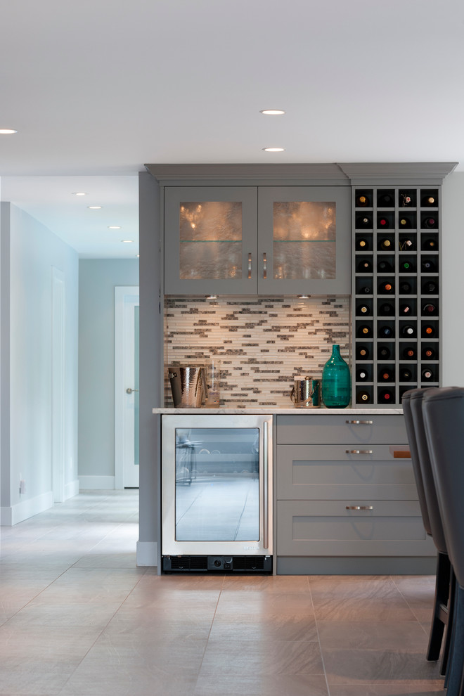 Inspiration for a large transitional home bar in Vancouver with an undermount sink, shaker cabinets, quartz benchtops, grey splashback, mosaic tile splashback, porcelain floors and grey cabinets.
