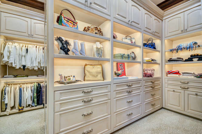 Photo of an expansive mediterranean gender-neutral walk-in wardrobe in Tampa with raised-panel cabinets, distressed cabinets, carpet and beige floor.