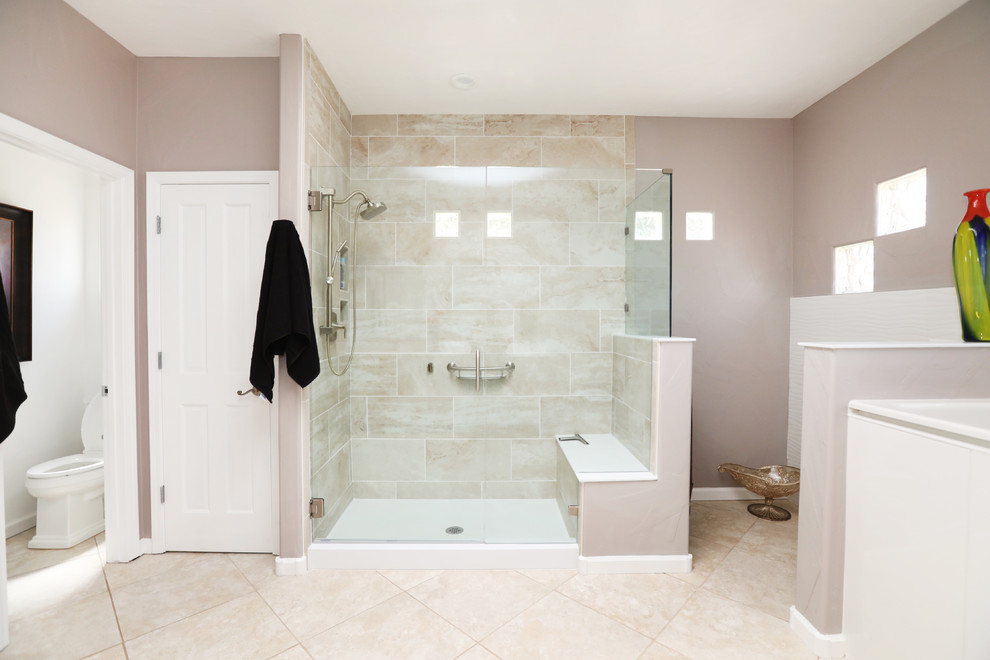 This is an example of a modern master bathroom in Albuquerque with recessed-panel cabinets, medium wood cabinets, a corner shower, a one-piece toilet, ceramic tile, an integrated sink, multi-coloured floor and white benchtops.