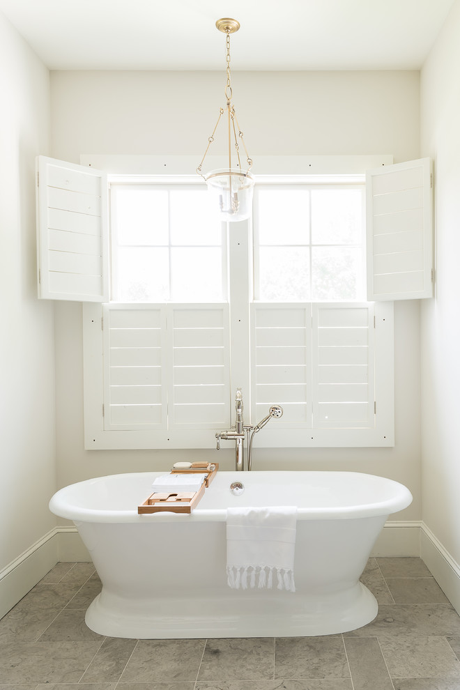 This is an example of a transitional master bathroom in Nashville with a freestanding tub, white walls and grey floor.