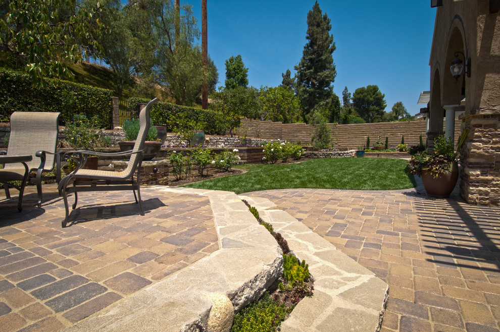 Inspiration for a mid-sized mediterranean backyard concrete paver patio remodel in Orange County with a roof extension