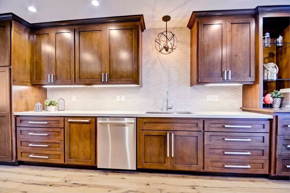 This is an example of a mid-sized country galley separate kitchen in San Diego with an undermount sink, shaker cabinets, dark wood cabinets, solid surface benchtops, white splashback, matchstick tile splashback, stainless steel appliances and medium hardwood floors.