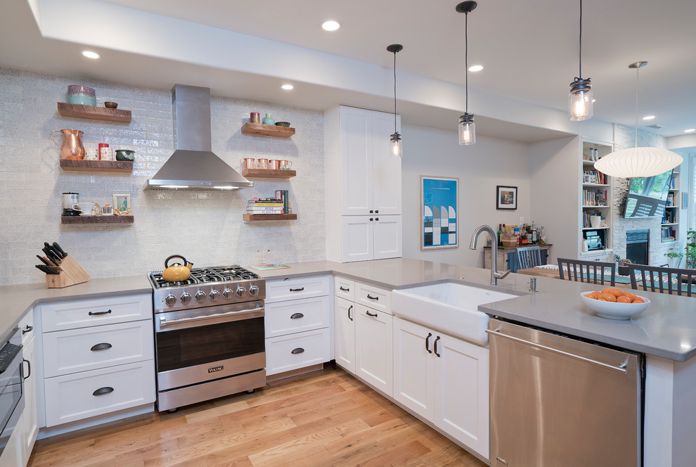 Design ideas for a mid-sized country u-shaped open plan kitchen in DC Metro with an undermount sink, shaker cabinets, white cabinets, solid surface benchtops, white splashback, brick splashback, stainless steel appliances, light hardwood floors, a peninsula, beige floor and grey benchtop.