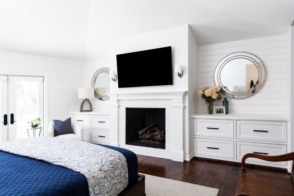 Inspiration for a mid-sized country master bedroom in Dallas with white walls, porcelain floors, a standard fireplace, a brick fireplace surround and brown floor.