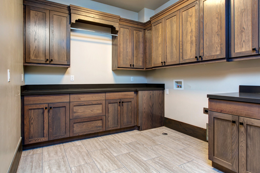 This is an example of a traditional galley dedicated laundry room in Salt Lake City with recessed-panel cabinets, dark wood cabinets, granite benchtops, white walls, travertine floors, a side-by-side washer and dryer, beige floor and black benchtop.