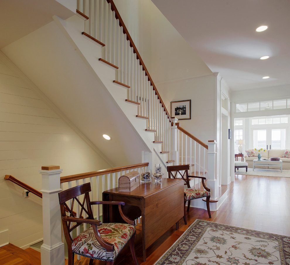 This is an example of a large beach style wood l-shaped staircase in Charleston with wood risers, wood railing and planked wall panelling.