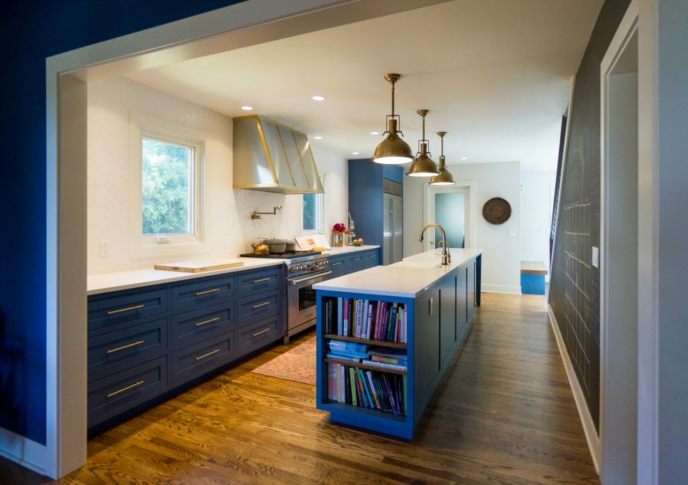 This is an example of a mid-sized contemporary kitchen in Seattle with a farmhouse sink, white splashback, ceramic splashback, stainless steel appliances, medium hardwood floors, with island and white benchtop.