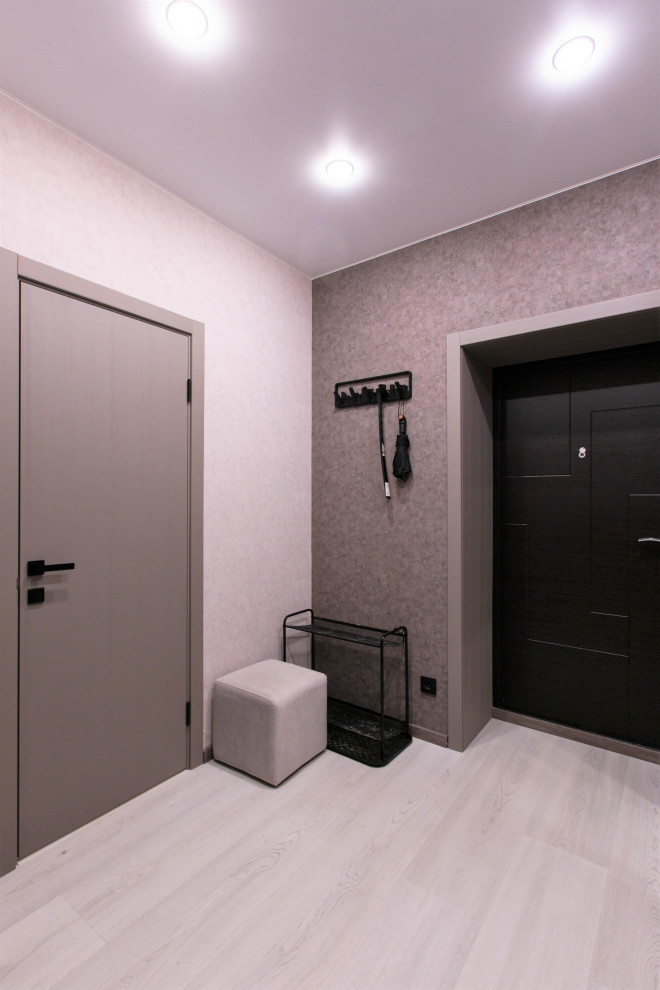 На фото: узкая прихожая среднего размера со шкафом для обуви в современном стиле с серыми стенами, полом из ламината, одностворчатой входной дверью, черной входной дверью, белым полом и обоями на стенах с