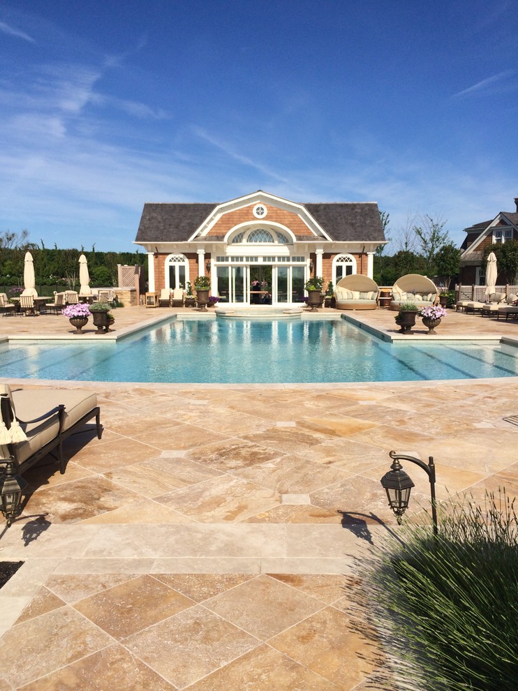 Photo of a large mediterranean backyard custom-shaped lap pool in New York with a pool house and natural stone pavers.