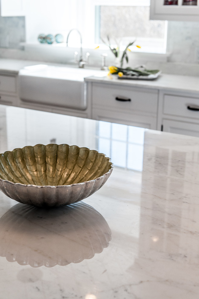Eat-in kitchen - large transitional l-shaped medium tone wood floor and brown floor eat-in kitchen idea in Boston with a farmhouse sink, shaker cabinets, white cabinets, gray backsplash, paneled appliances, an island, marble countertops and marble backsplash