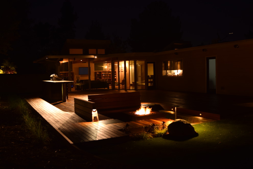This is an example of a large modern partial sun backyard landscaping in San Francisco with a fire pit and decking.