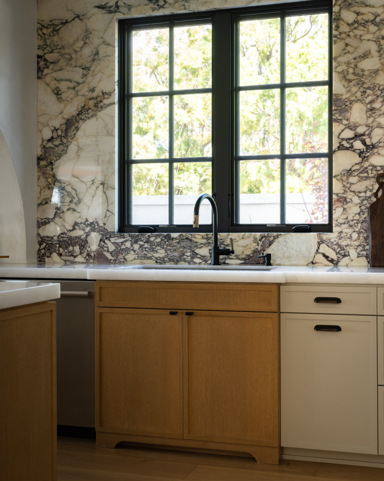 Example of a transitional light wood floor kitchen design in Orange County with recessed-panel cabinets and marble backsplash