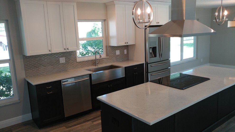 Inspiration for a mid-sized transitional galley vinyl floor and gray floor open concept kitchen remodel in Tampa with a farmhouse sink, shaker cabinets, white cabinets, quartz countertops, gray backsplash, ceramic backsplash, stainless steel appliances and an island