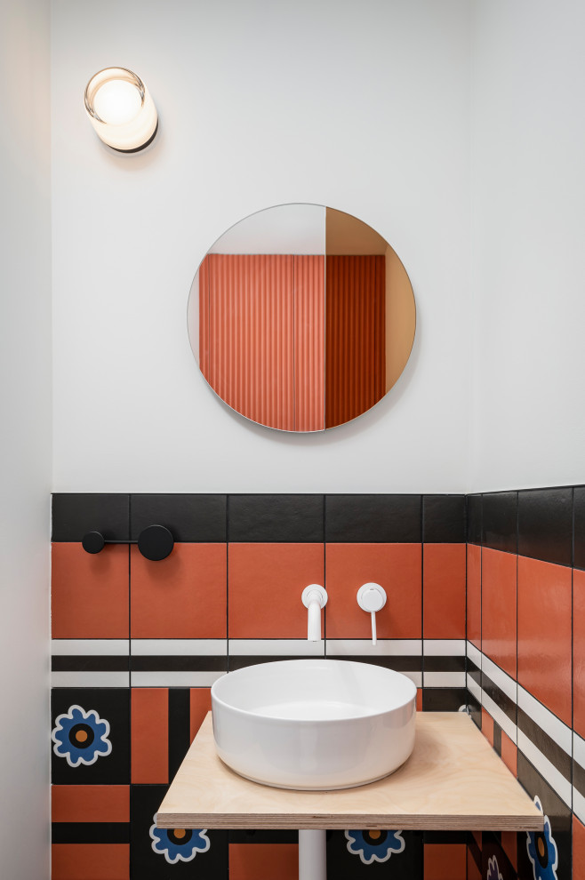 Inspiration for a small contemporary powder room in Toronto with a wall-mount toilet, black and white tile, ceramic tile, concrete floors, a vessel sink, wood benchtops, a floating vanity and panelled walls.