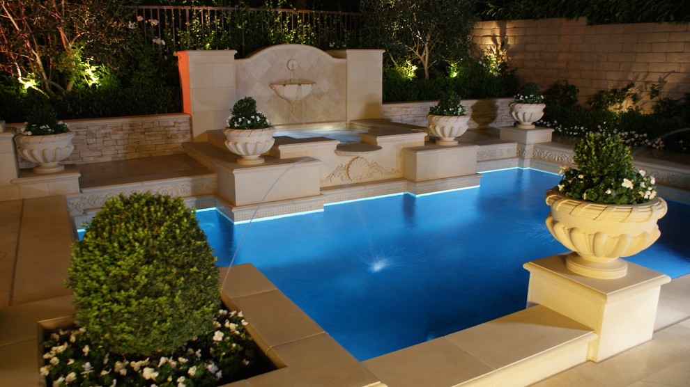 Inspiration for a small mediterranean backyard custom-shaped pool in Orange County with a water feature and concrete pavers.