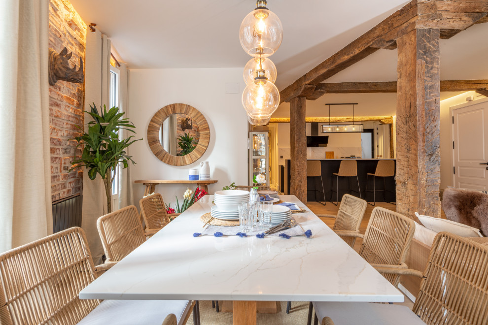 Photo of a large beach style open plan dining in Bilbao with white walls, beige floor and brick walls.