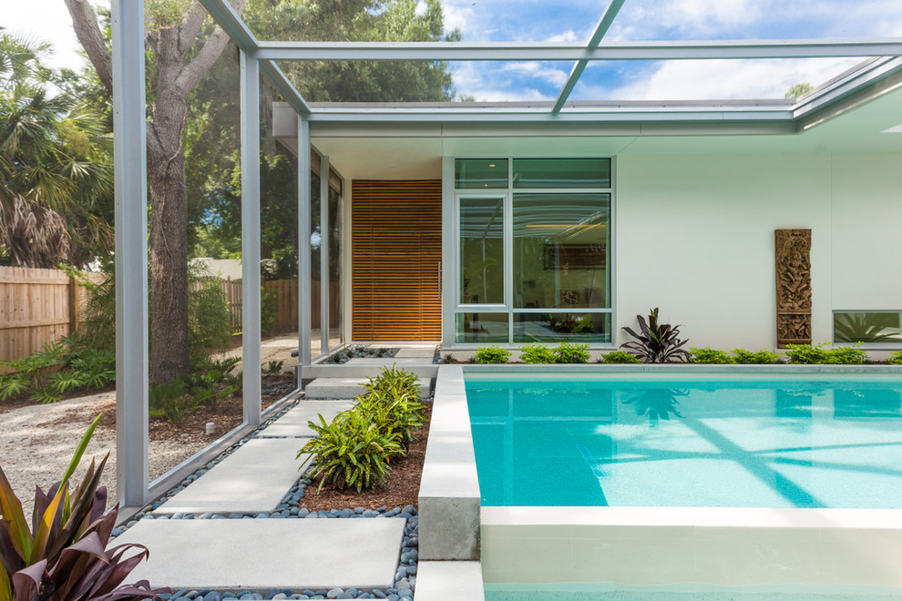Photo of a mid-sized modern backyard rectangular infinity pool in Other with a hot tub and concrete pavers.