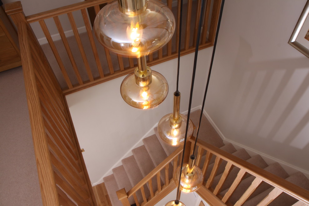 Contemporary carpeted u-shaped staircase in Cheshire with carpet risers and wood railing.