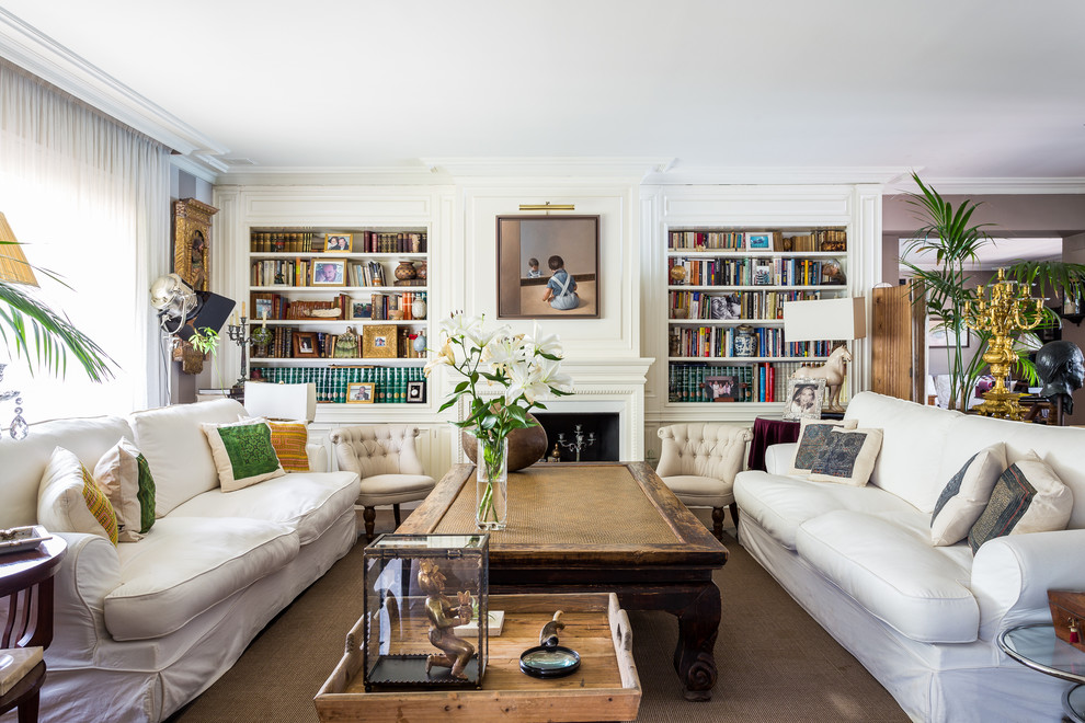Large mediterranean open concept living room in Madrid with a library, white walls, carpet and no tv.