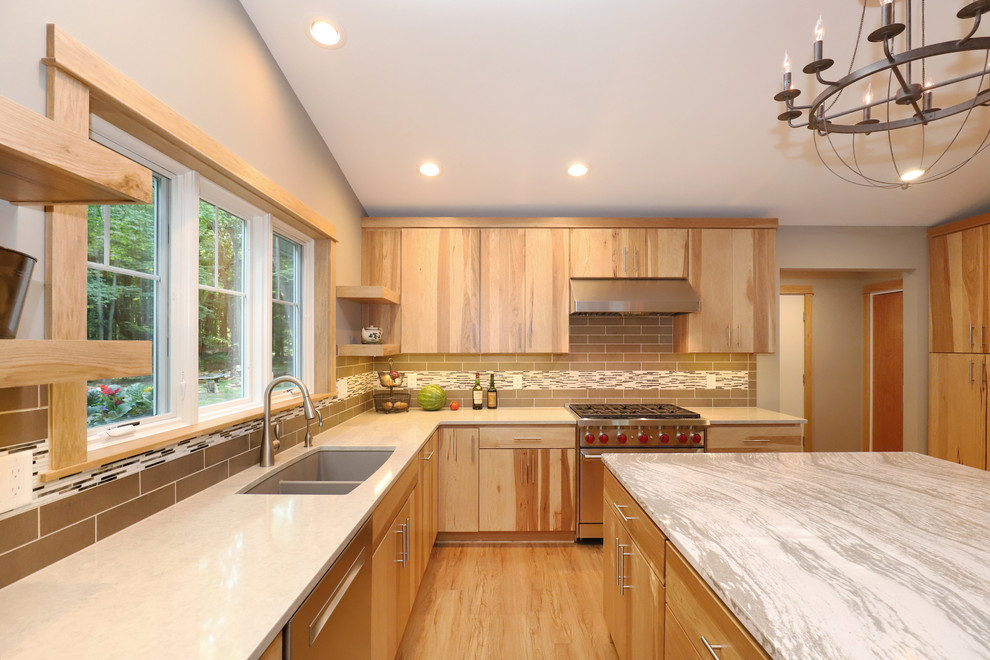 Inspiration for a mid-sized transitional u-shaped light wood floor and brown floor eat-in kitchen remodel in Grand Rapids with an undermount sink, flat-panel cabinets, light wood cabinets, quartz countertops, brown backsplash, ceramic backsplash, stainless steel appliances and an island
