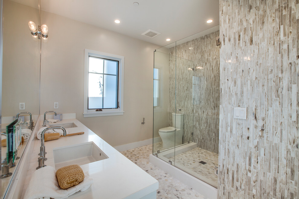 Beach style 3/4 bathroom in Los Angeles with a corner shower, a two-piece toilet, brown tile, beige walls, pebble tile floors and an undermount sink.