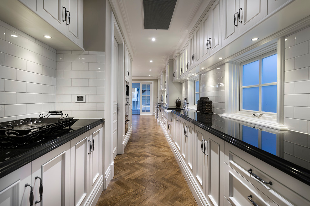Inspiration for an expansive traditional galley kitchen in Perth with an undermount sink, recessed-panel cabinets, beige cabinets, granite benchtops, white splashback, ceramic splashback, stainless steel appliances, dark hardwood floors and with island.