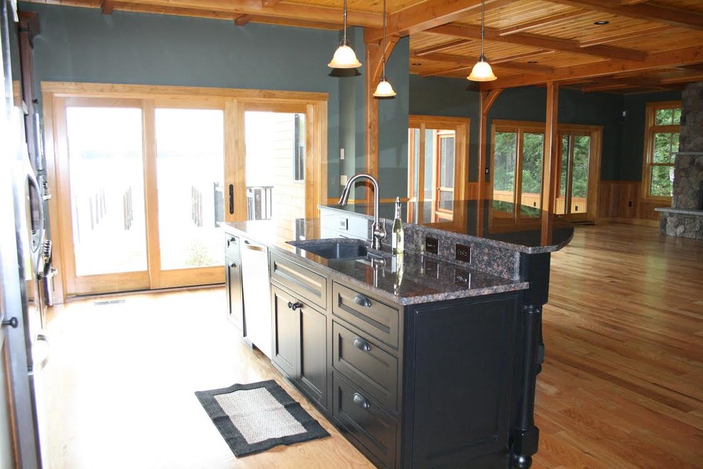 Large mountain style single-wall light wood floor eat-in kitchen photo in Boston with an undermount sink, shaker cabinets, black cabinets, granite countertops, stainless steel appliances and an island