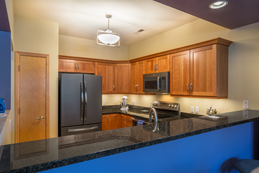 Mid-sized transitional u-shaped light wood floor open concept kitchen photo with an undermount sink, shaker cabinets, medium tone wood cabinets, granite countertops, black appliances, no island and black countertops